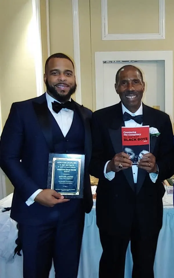 Miguel Jones holding an award plaque at a formal event